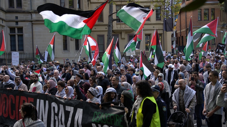 People holding Palestinian flags march during a rally in Sydney. 