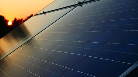 Solar panels on a roof as the sun rises in the background