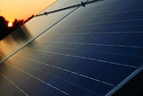 Solar panels on a roof as the sun rises in the background