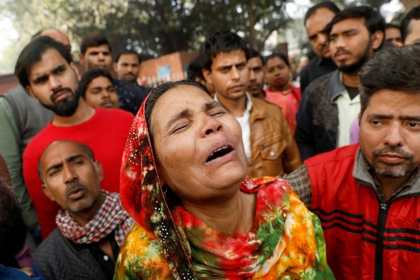 A woman cries surrounded by other people