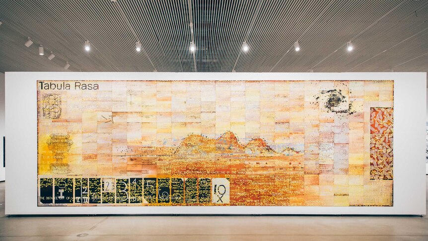 A large landscape painting made up of many small canvas boards, showing mountains and the words "Tabula Rasa"