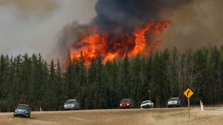 A wildfire burns as evacuees who were stranded north of Fort McMurray head south.