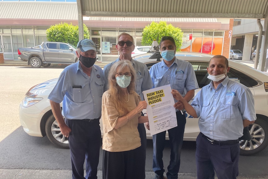 A woman is standing in the middle of a group of men in uniform with a petition in her handS 