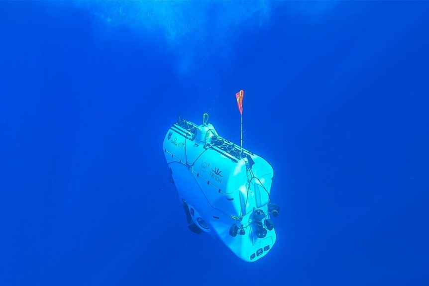 A small, light-coloured submarine deep down in the ocean.