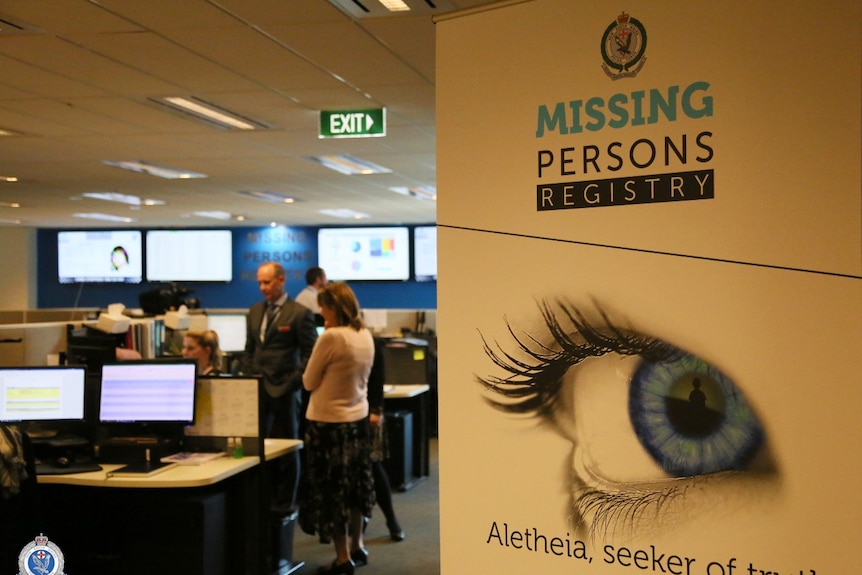 A group of people at a computer next to sign saying missing persons registry.