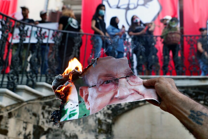 An anti-government protester burns a picture of Lebanese President Michel Aoun inside the Lebanese foreign ministry in Beirut.