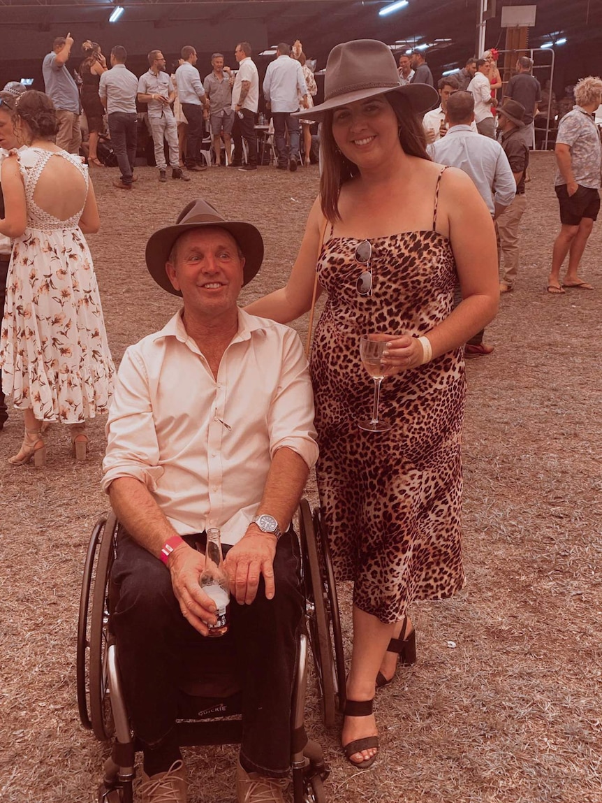 Man in a wheelchair with lady standing next to him.