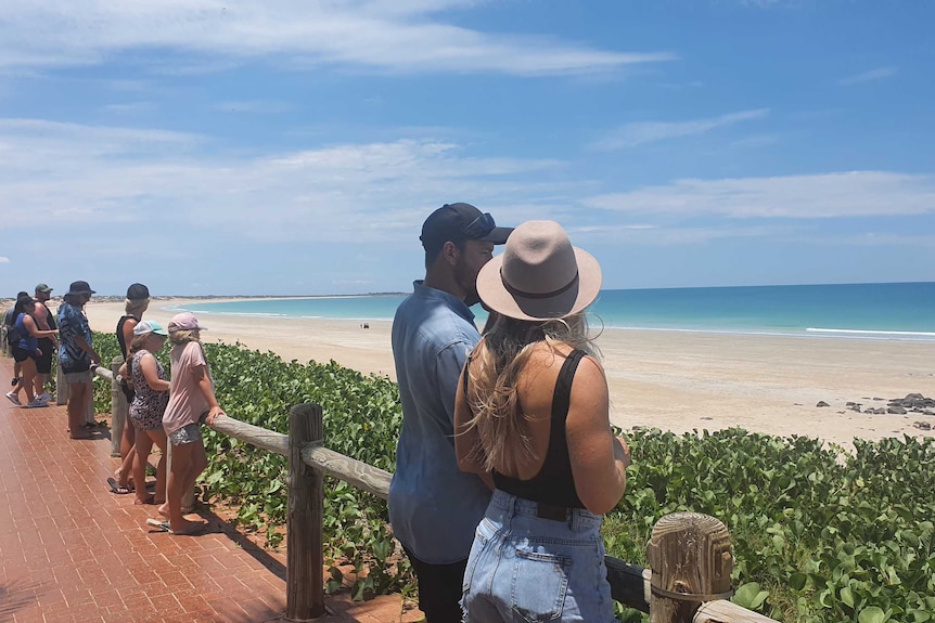 People gather along a pathway overlooking the ocean