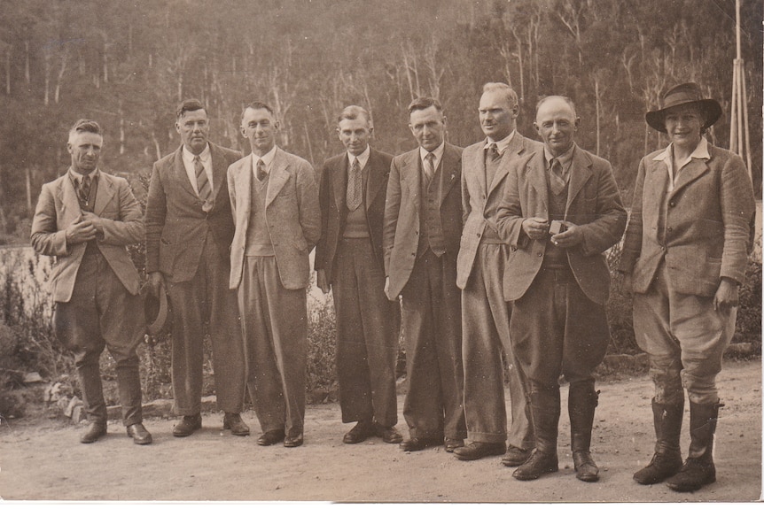 Black and white photograph of men in suits with one woman.