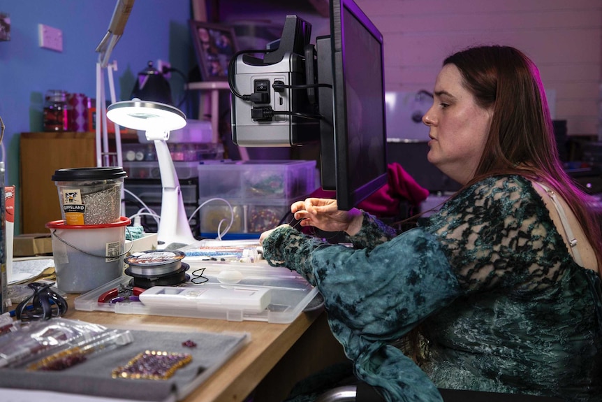 Asha Martin works on her beading project at a desk.