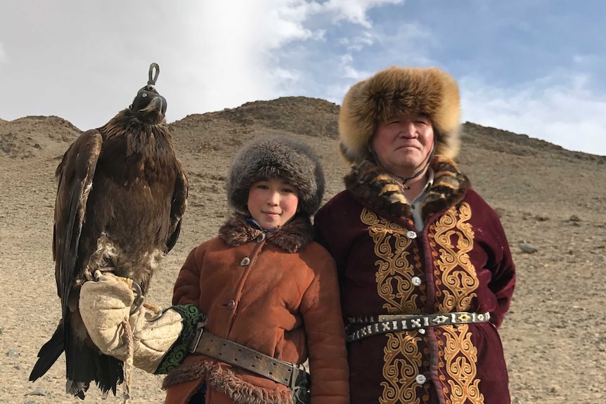 Golden eagle hunter Akbota Baitilkarib and her dad Orken pose with an eagle.