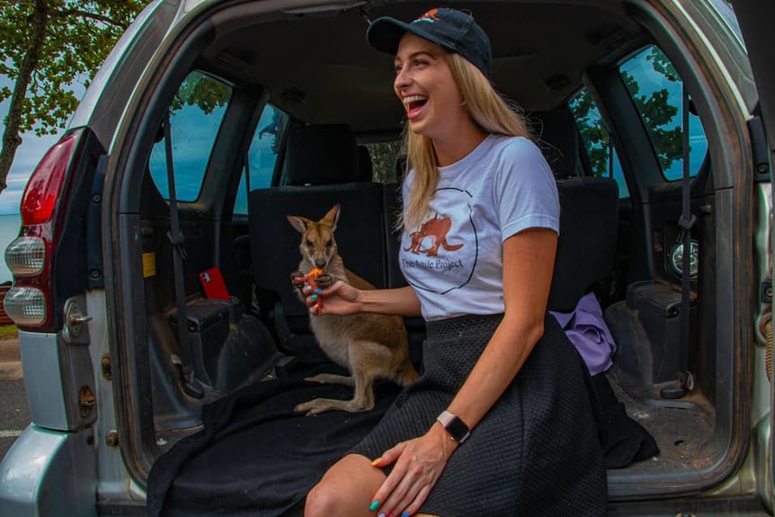 woman with wallaby in back of car