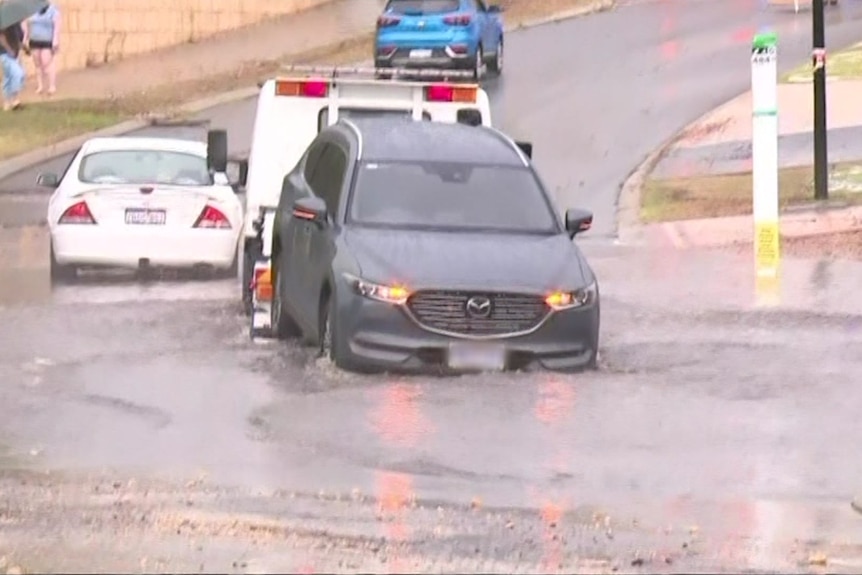 A car being towed through a large puddle. 