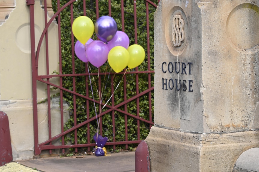 purple and yellow balloons sit next to a sign reading court house