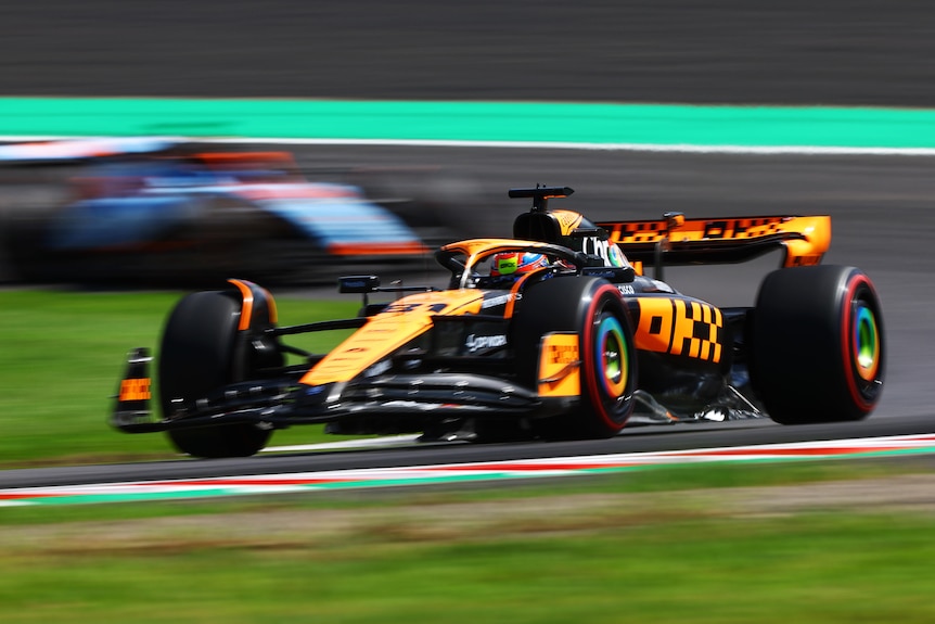 An orange F1 car goes through a set of corners on a track