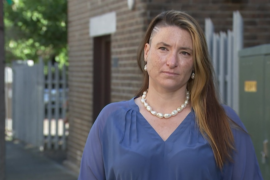 A woman in a purple shirt stares off camera.