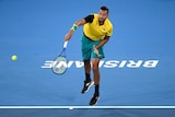 An Australian tennis player is captured mid-serve, with his racquet in the follow-through.