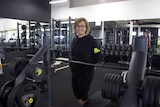 A woman stands among gym equipment.