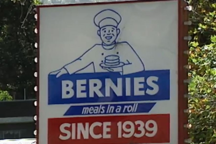 Blue white and red sign of man in chef outfit holding plate with burger on it