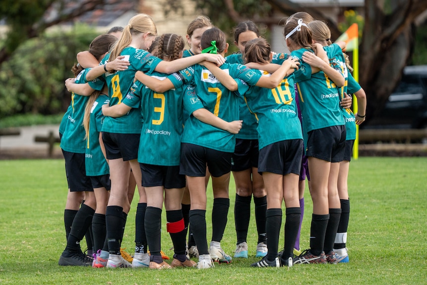 A team of soccer players huddle before a game.