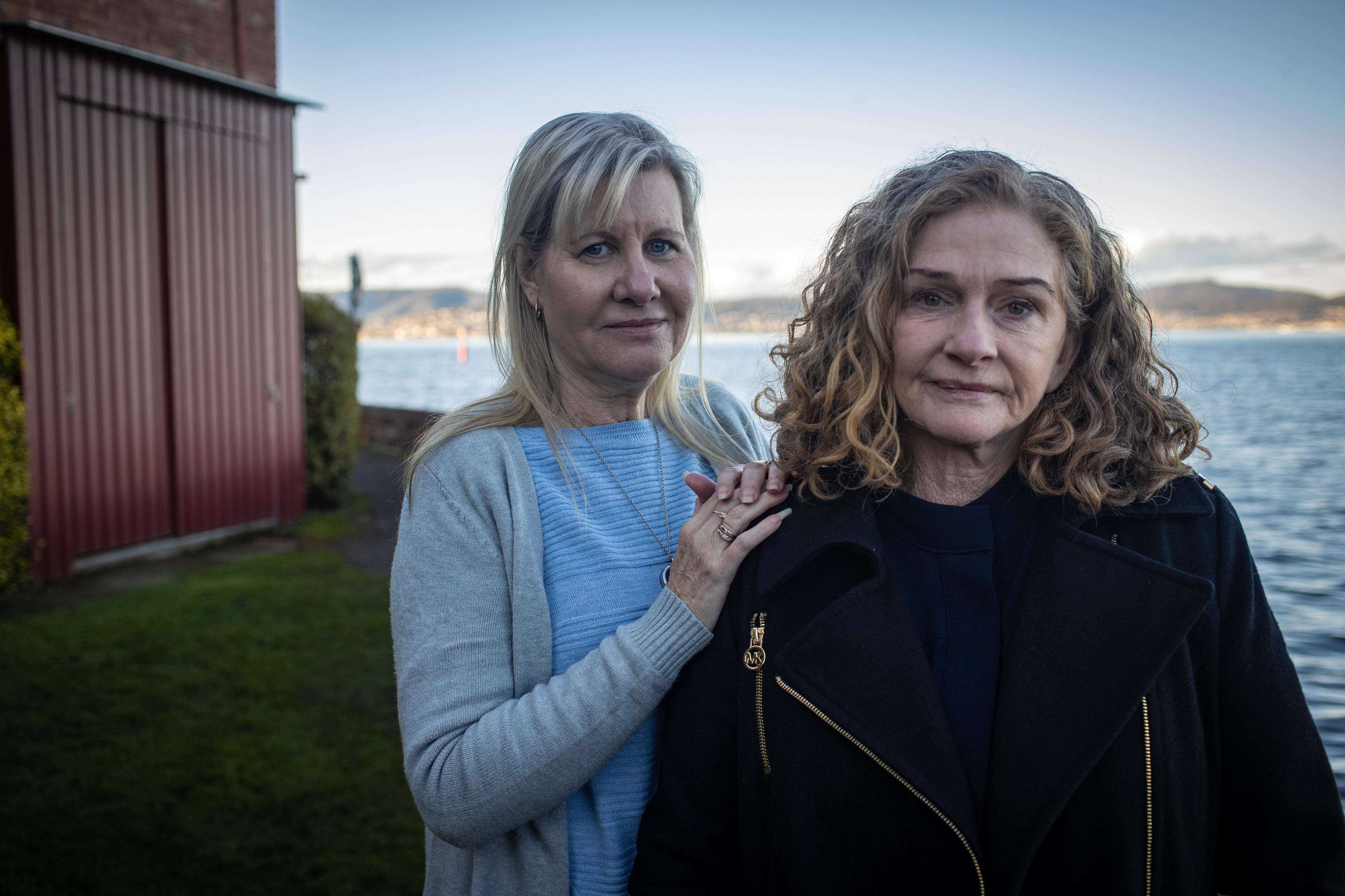 A woman rests her hands on another woman's shoulder in a show of support.