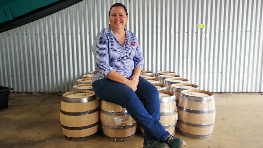 Sarina Sugar Shed head distiller Sarah Parrott sitting on rum barrels