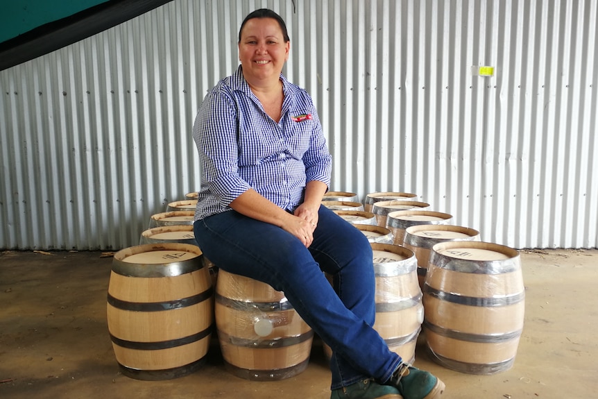 Sarina Sugar Shed head distiller Sarah Parrott sitting on rum barrels
