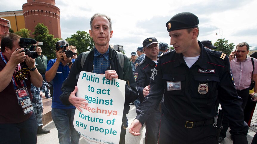A British LGBTQ activist is arrested holding a sign which reads "Putin fails to act against Chechnya torture of gay people"