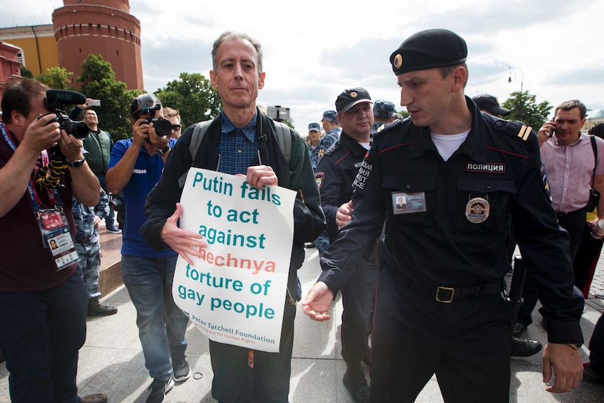 A British LGBTQ activist is arrested holding a sign which reads "Putin fails to act against Chechnya torture of gay people"