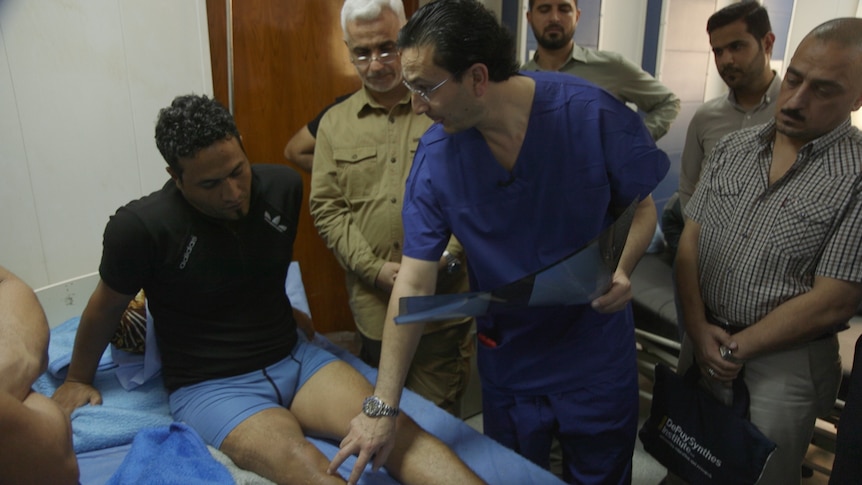 Dr Munjed Al Muderis examines a patient's leg.