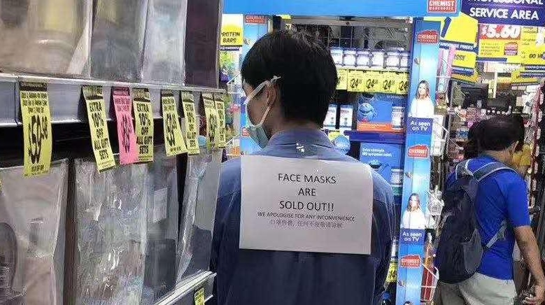 A staff member wears a sign saying 'face masks are sold out'