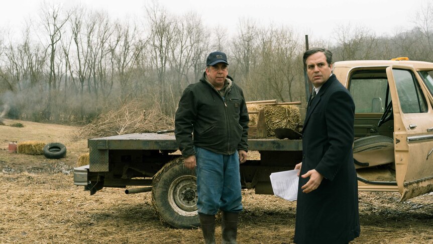 The actors Bill Camp as a farmer and Mark Ruffalo as a lawyer standing in a dry farm field with a pickup truck