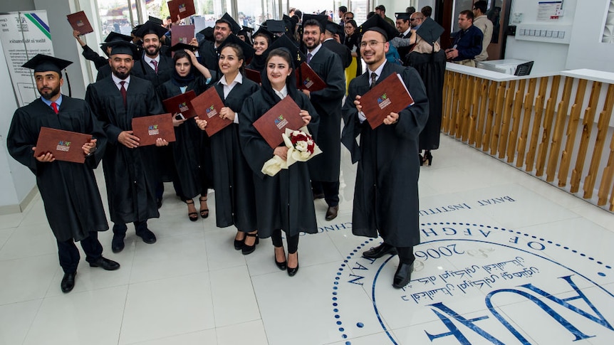 Afghan students from the American University of Afghanistan (AUAF) hold up their diplomas after graduating