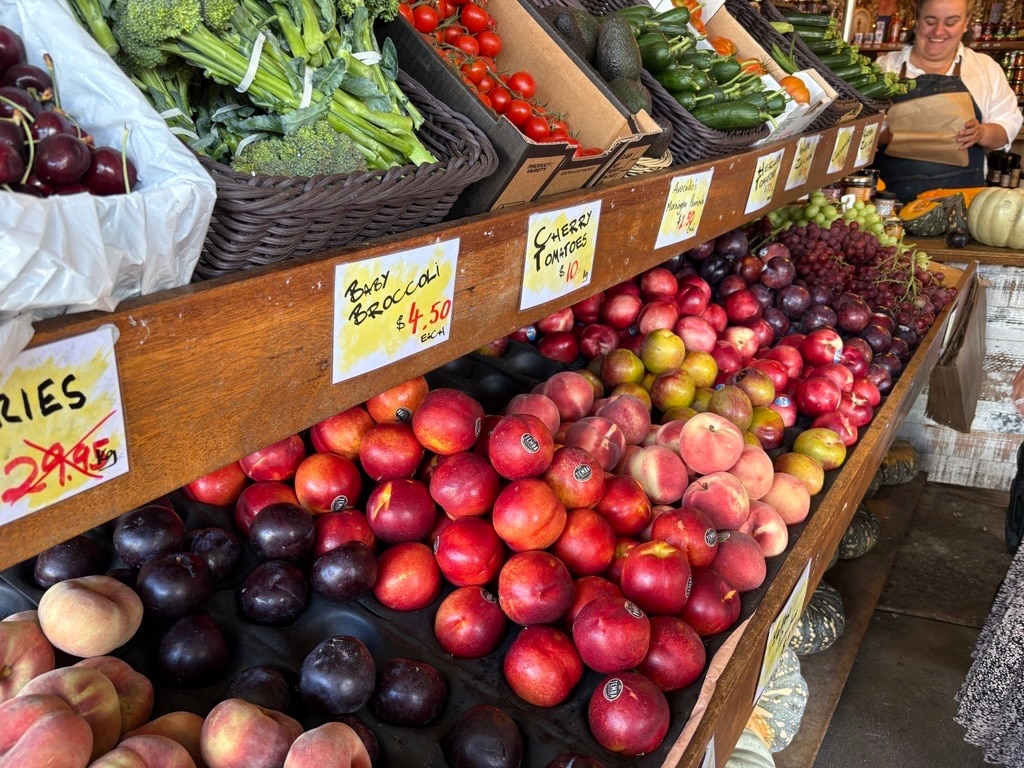 Un puesto en el mercado que vende productos frescos como ciruelas, nectarinas y melocotones.