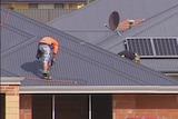 Workers attach a roof to a new home