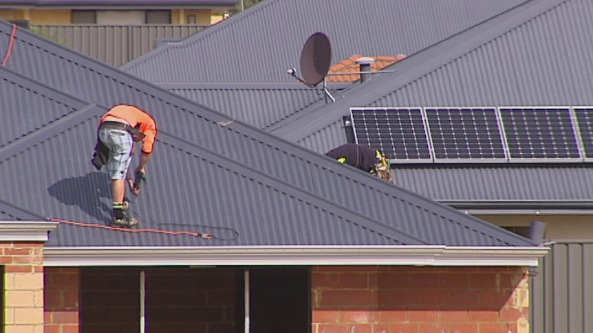 Workers attach a roof to a new home