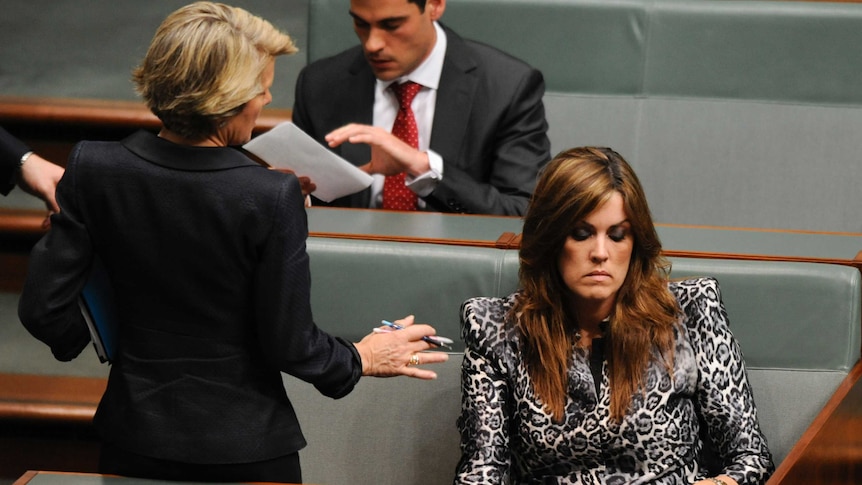 One woman standing and talking to another woman sitting in Parliament House