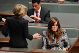 One woman standing and talking to another woman sitting in Parliament House