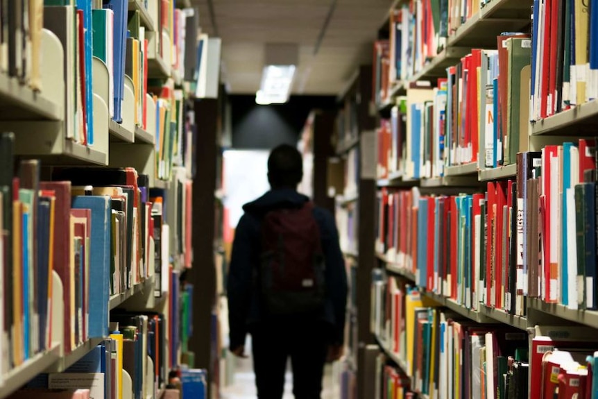 A silhouette of a student in a library.