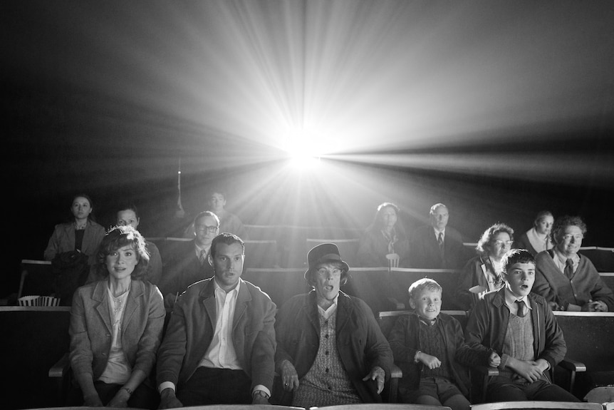 A black and white image of a family, including a teenage and young boy, and an older woman, in a 60s cinema