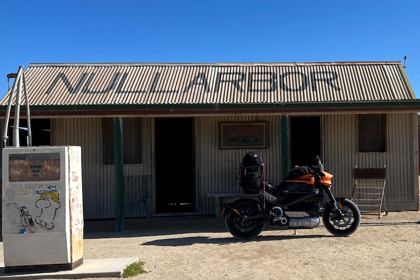 The orange and black electric Harley pictured in front of a Nullarbor roadhouse. 