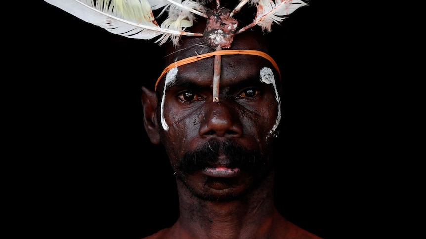 A portrait of an Indigenous man who is about to perform in a dancing troupe.