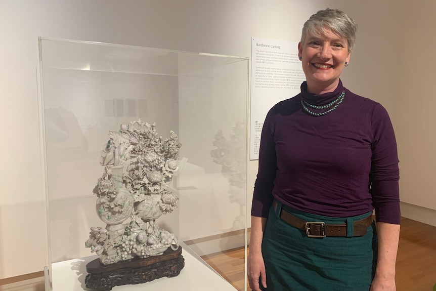 Dr Sophie Couchman standing beside a hand-carved white jade ornament at the Bendigo Art Gallery.