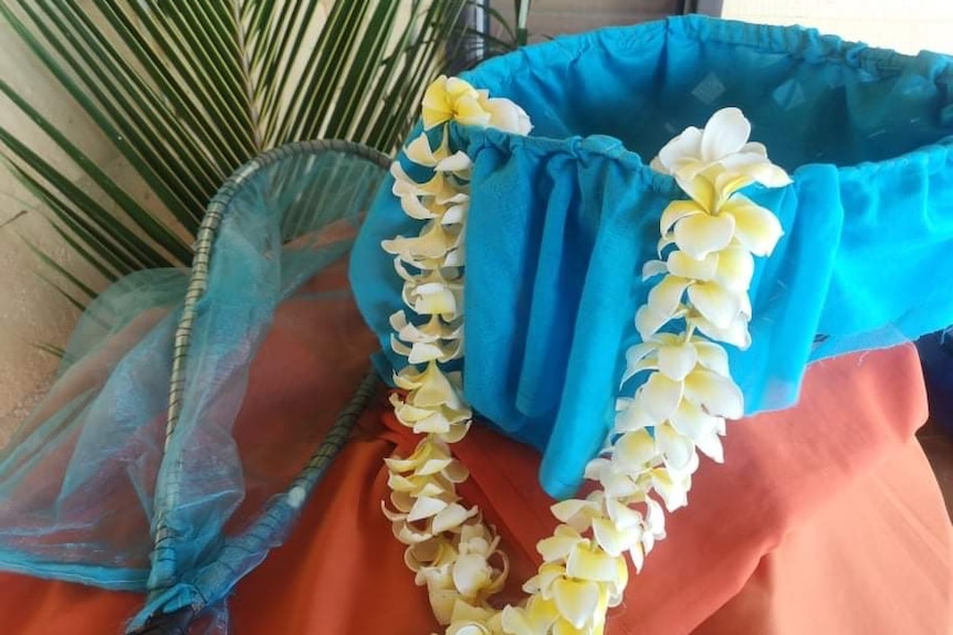 A yellow flower necklace sits next to a net.