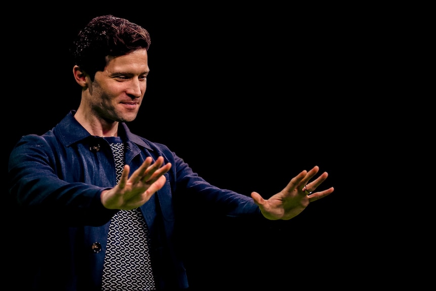 Astronomer Alan Duffy makes a guesture with his hands against a black background