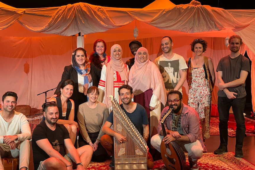 The Bukjeh creators and perfomers smile on the show's set, some holding instruments.