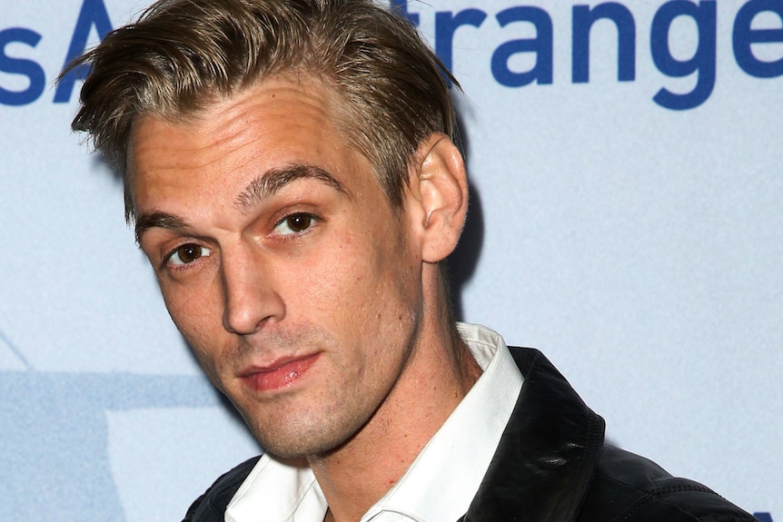 a close up image of Aaron Carter raising his eyebrows as he looks at the camera on a red carpet event
