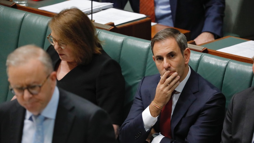 Jim Chalmers sitting in the House of Representatives. He holds his hand over his mouth.