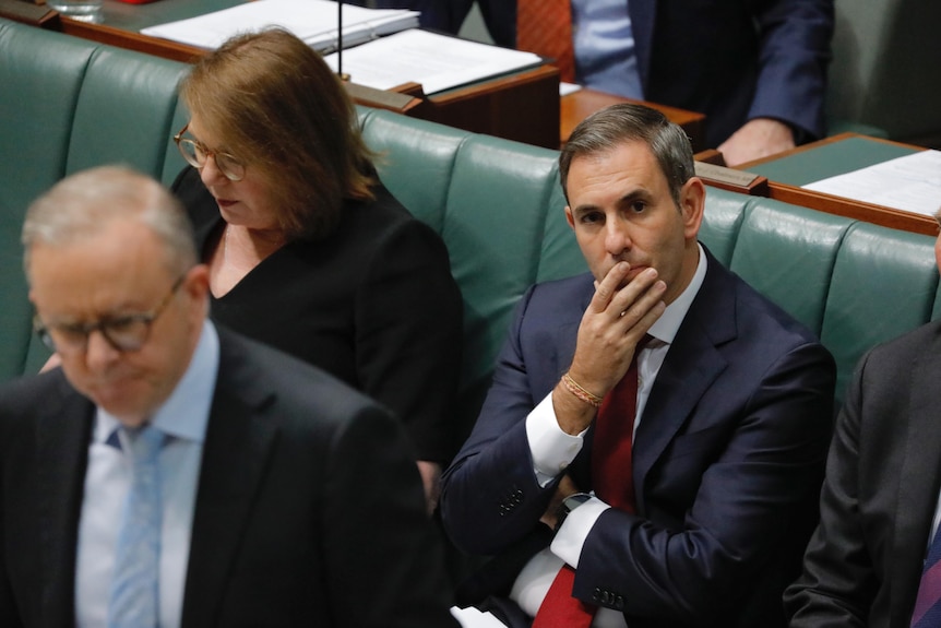 Jim Chalmers sitting in the House of Representatives. He holds his hand over his mouth.