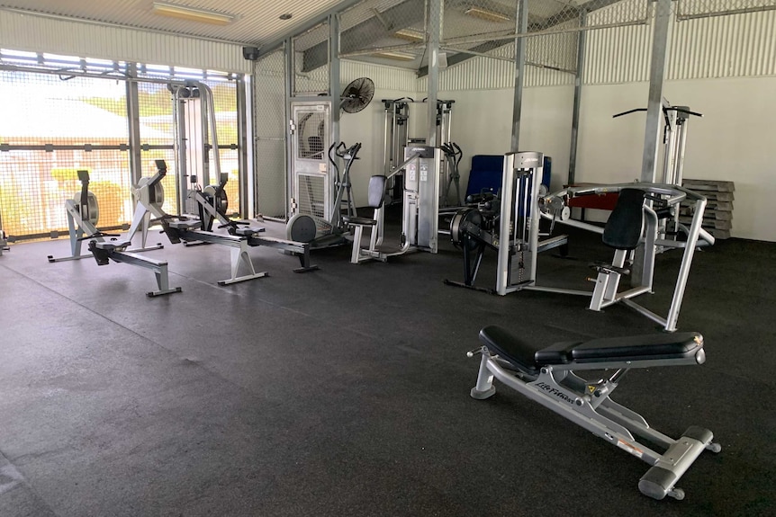 Gym equipment including rowing machines and exercise bikes in a structure that looks like a shed.